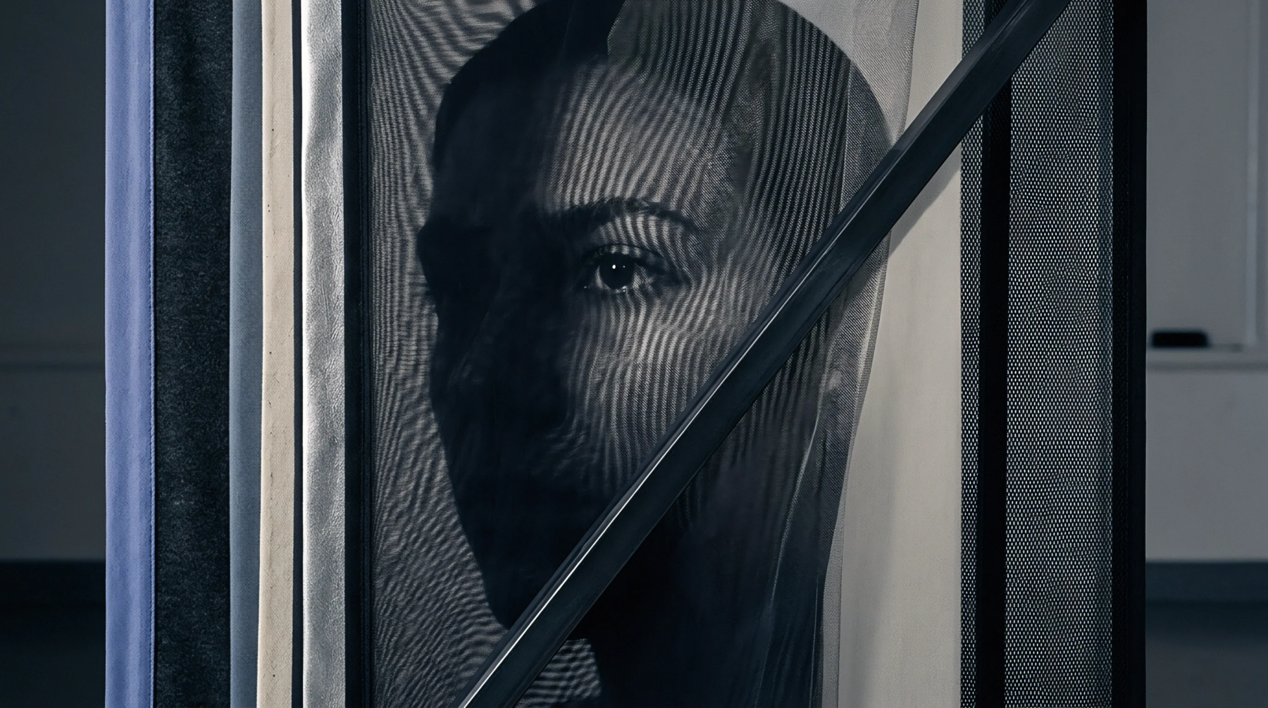 A synthetic black mesh screen stands between the viewer and a monochrome portrait printed on a dense white fabric backing.